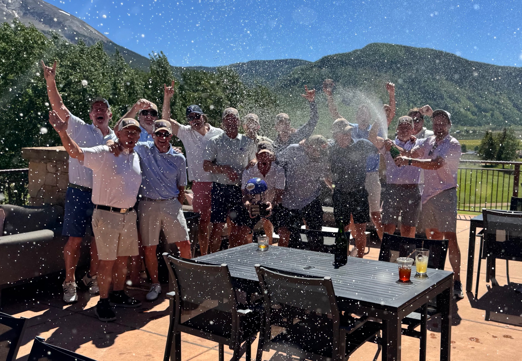 The Purple Helmet golfers celebrating together outdoors with the Rocky Mountains in the background